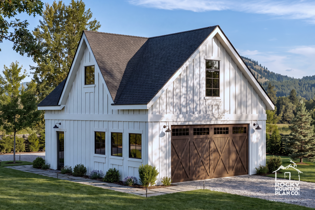 A modern farmhouse-style ADU house exterior with white vertical siding, a dark gray shingled gable roof, and a large brown garage door, shown on a landscaped lot with trees and mountains in the background. Rocky Mountain Plan Company